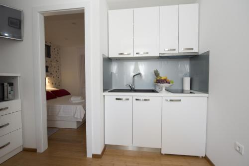 a kitchen with white cabinets and a sink and a bed at Apartments Annya in Split