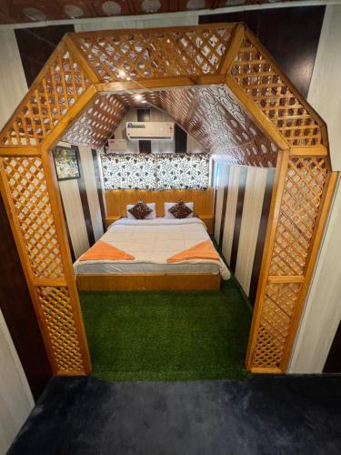 ein kleines Bett in einem Holzrahmen in einem Zimmer in der Unterkunft ARISTOTLE GROUP OF HOUSEBOATS & TRANSPORTATION in Srinagar