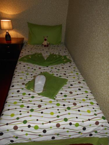 a bed with a green comforter with a stuffed animal on it at Guest House Nise in Tbilisi City