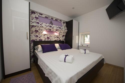a bedroom with a large bed with purple and white pillows at Apartments Annya in Split