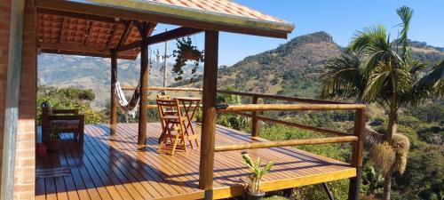 a wooden deck with a table and chairs on a mountain at Chalé Alto da Serra in Gonçalves