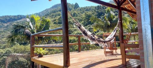 a hammock on a deck with a view of the mountains at Chalé Alto da Serra in Gonçalves