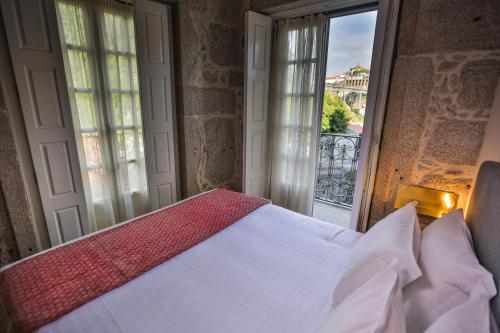 a bed sitting in front of a window next to a window at My Ribeira Guest House in Porto