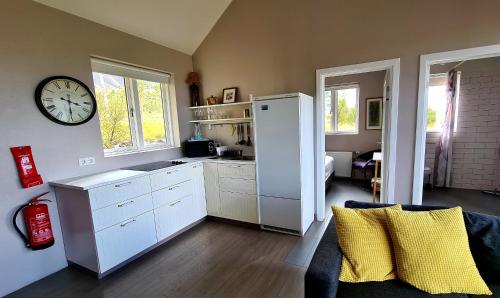 a kitchen with a refrigerator and a clock on the wall at Kría Cottages in Skeljabrekka