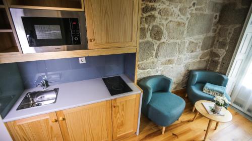a kitchen with a sink and a microwave and a chair at My Ribeira Guest House in Porto