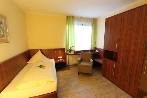 a bedroom with a bed and a desk and a chair at Akzent Hotel Jonathan in Lippstadt