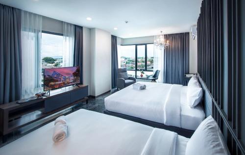 Habitación de hotel con 2 camas y TV de pantalla plana. en Sibtis Hotel en Lampang