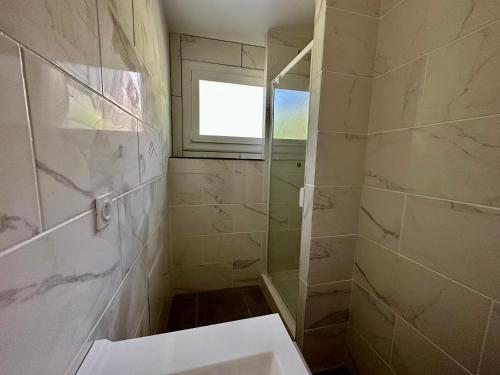 uma casa de banho com um chuveiro e um lavatório. em Appartement lumineux em La Bâtie-Neuve
