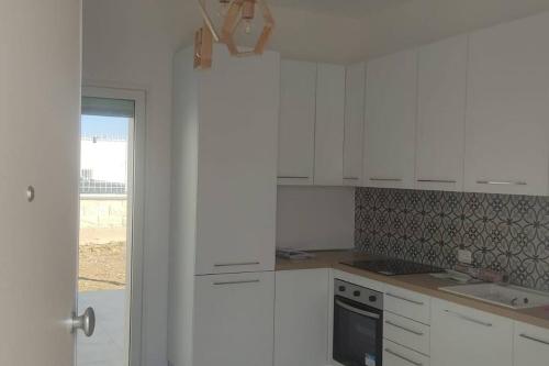 uma cozinha branca com armários brancos e uma janela em AltamareA Casa vacanze em Brucoli
