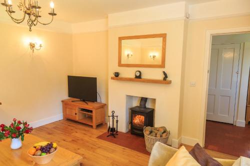 a living room with a fireplace and a television at The Old Chemist in Burley