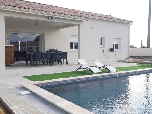 a house with a swimming pool with chairs and a table at Gîte pour 8 personnes in Frespech