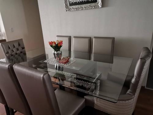 een glazen eettafel met stoelen en een vaas met bloemen bij Condominio Villa Verde 2 in Arequipa