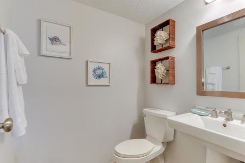 y baño con aseo, lavabo y espejo. en Luxe Island Condo with Deck Play, Swim and Relax!, en Oceanmarsh Subdivision