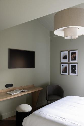 a bedroom with a bed and a desk and a tv at Hotel Porte Brunet in Saint-Émilion