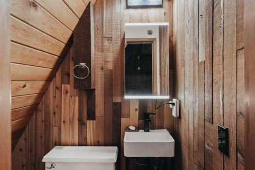 ein Badezimmer mit Holzwänden, einem Waschbecken und einem WC in der Unterkunft Majestic A-Frame on 5 acres! in Sisters