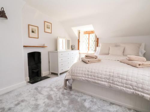 a white bedroom with a bed and a fireplace at Jasmine Cottage in Chester