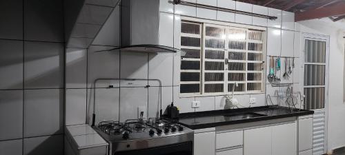 a white kitchen with a stove and a sink at Sitio Chacara temporada Lindoia Villa Vale in Lindóia
