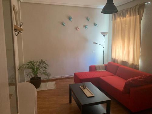 sala de estar con sofá rojo y pájaros en la pared en Apartamento a 200 metros paseo zorrilla en Valladolid