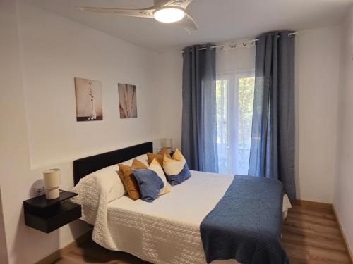 een slaapkamer met een bed met blauwe kussens en een raam bij Apartamento El olivo in Empuriabrava