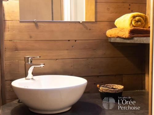 La salle de bains est pourvue d'un lavabo blanc et d'un mur en bois. dans l'établissement les Gîtes de l'Orée Perchoise, à Saint-Marc-du-Cor