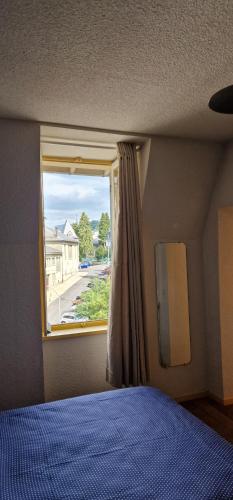 a bedroom with a bed and a window at Hotel ChezJeanne in La Bourboule