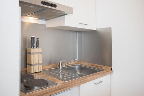 Una cocina con fregadero y gabinetes blancos. en Welcome in - Apartments Am Waltenberg 57-59, en Winterberg
