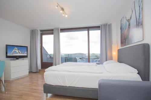 Un dormitorio con una cama grande y una ventana grande. en Welcome in - Apartments Am Waltenberg 57-59, en Winterberg