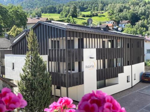 an office building with black and white facade with pink flowers at Pension & Residence Astoria in Prato allo Stelvio