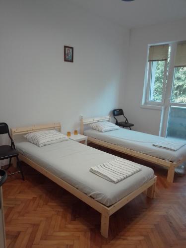 two beds in a room with wooden floors and windows at Стеди - стая за гости in Varna City