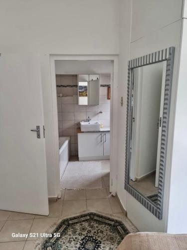 a bathroom with a mirror and a tub and a sink at 1 bedroom Morleen Park apartment in Swakopmund