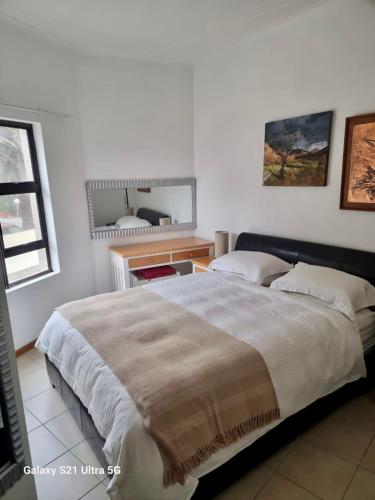 a bedroom with a large bed and a mirror at 1 bedroom Morleen Park apartment in Swakopmund