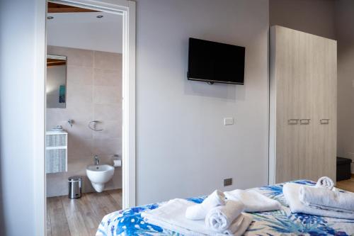 a bedroom with a bed with a television and a bathroom at Il Beccaria Relais B&B in Fondi