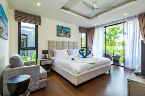 um quarto com uma cama, uma cadeira e uma janela em Laguna Park Villa with rooftop pool by Lofty em Praia de Bang Tao