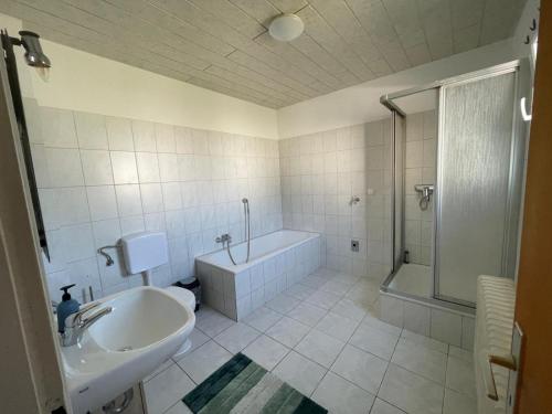 ein Bad mit einer Badewanne, einem Waschbecken und einer Dusche in der Unterkunft FeWo SüMeer 7 in Wilhelmshaven