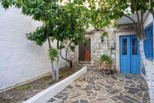 a house with a blue door and trees in front at Nick and Avge's Stone House in Polichnítos