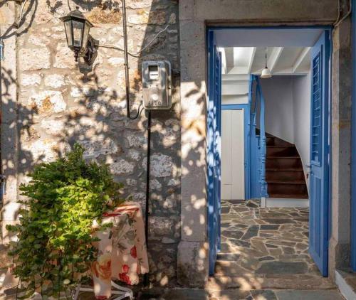 a building with a blue door and a plant at Nick and Avge's Stone House in Polichnítos