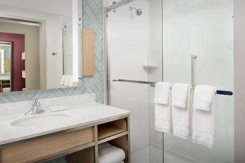 a bathroom with a sink and a shower with towels at Hilton Garden Inn Orlando Downtown in Orlando