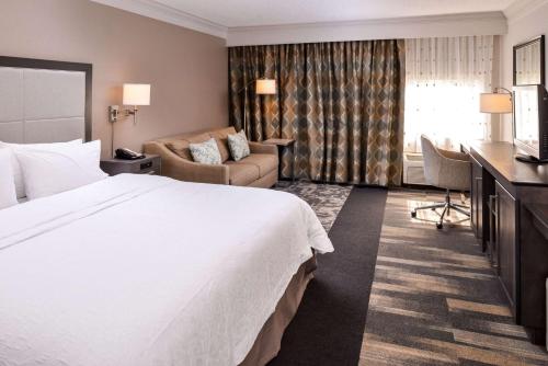 a hotel room with a large bed and a couch at Hampton Inn Fort Lauderdale Plantation in Plantation