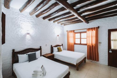 a bedroom with two beds and a window at Hotel Casa Barbara Holbox in Holbox Island
