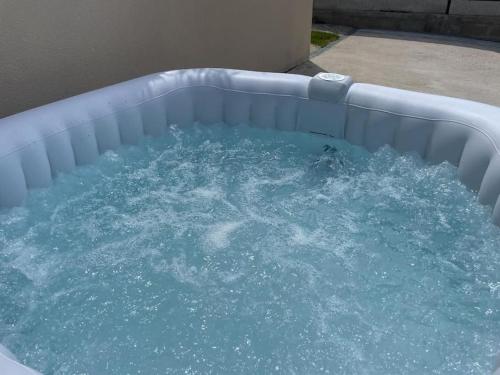 un bain à remous rempli d'eau bleue dans une arrière-cour dans l'établissement La villa des quais de Seine et jacuzzi prox Paris, à Sartrouville