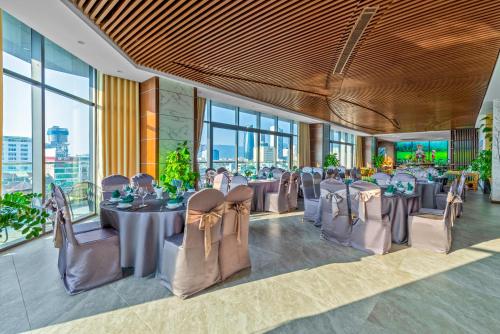 a banquet hall with tables and chairs and windows at G8 Luxury Hotel and Spa Da Nang in Da Nang