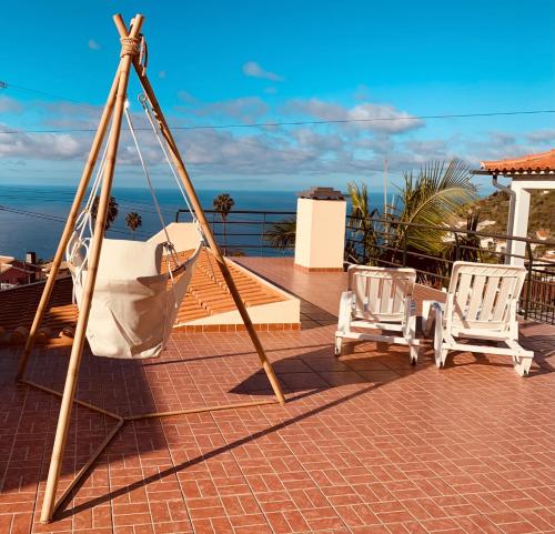 a porch with two chairs and a swing at BnB BananaTree House in Arco da Calheta