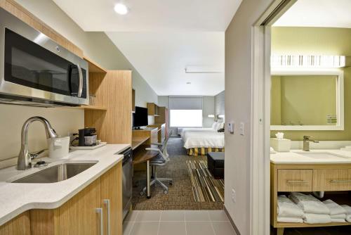 a kitchen with a sink and a room with a bed at Home2 Suites by Hilton Dallas Downtown at Baylor Scott & White in Dallas