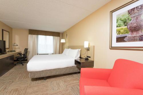 a hotel room with a bed and a red couch at Hilton Garden Inn West Lafayette Wabash Landing in Lafayette