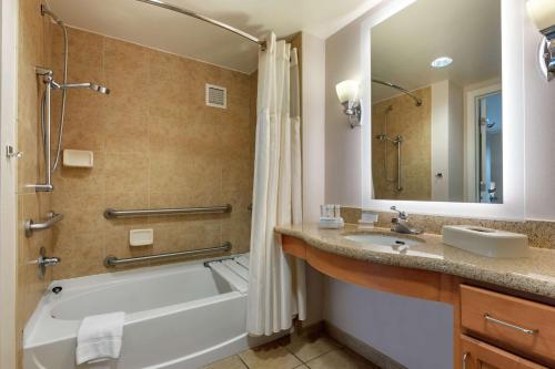 ein Badezimmer mit einer Badewanne, einem Waschbecken und einem Spiegel in der Unterkunft Homewood Suites by Hilton Daytona Beach Speedway-Airport in Daytona Beach