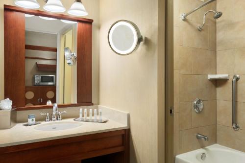 a bathroom with a sink and a shower with a mirror at DoubleTree by Hilton DFW Airport North in Irving