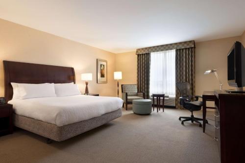 a hotel room with a bed and a desk and a television at Hilton Garden Inn Dulles North in Ashburn