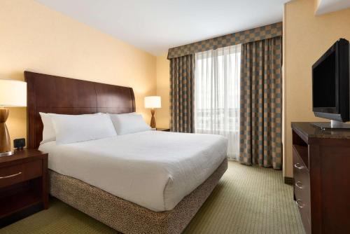 a hotel room with a bed and a flat screen tv at Hilton Garden Inn Dulles North in Ashburn