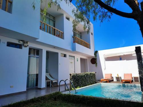 Villa con piscina frente a un edificio en Paracas Guest House, en Paracas