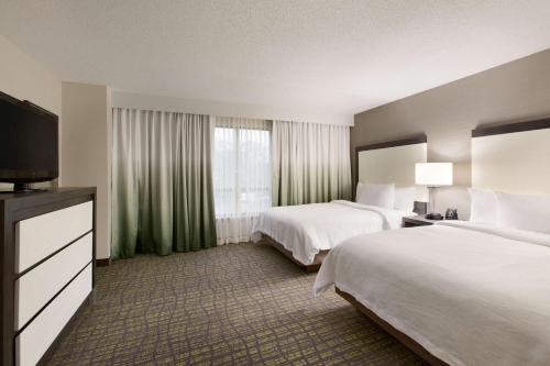 a hotel room with two beds and a flat screen tv at Embassy Suites Newark - Wilmington/South in Newark